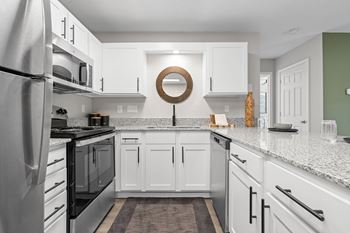 A modern kitchen with white cabinets and a stainless steel refrigerator.
